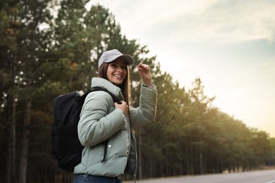 Woman with backpack on road near forest