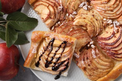 Photo of Tasty apple pie with chocolate topping, fresh fruits and green leaves on table, flat lay