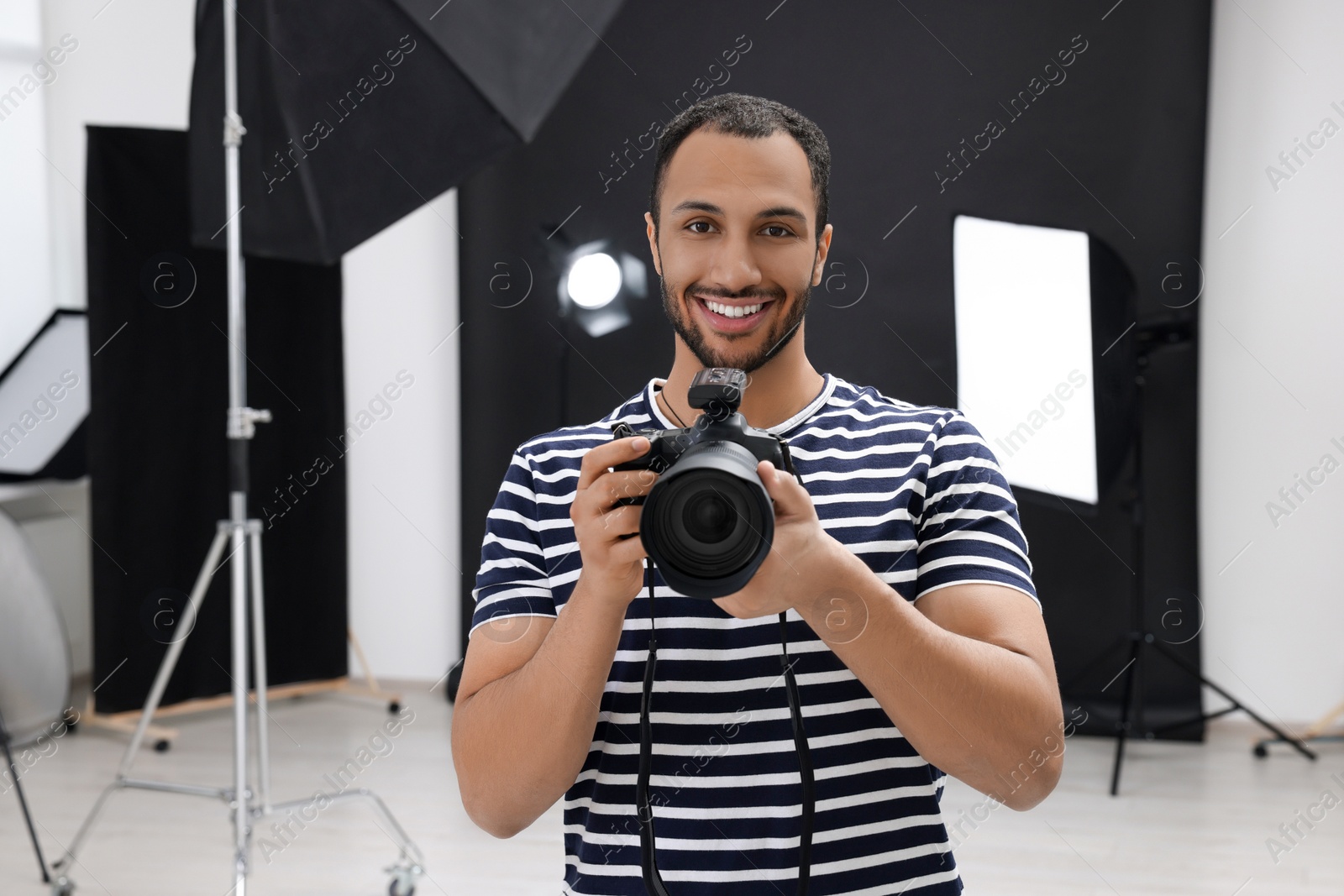 Photo of Young professional photographer with camera in modern photo studio