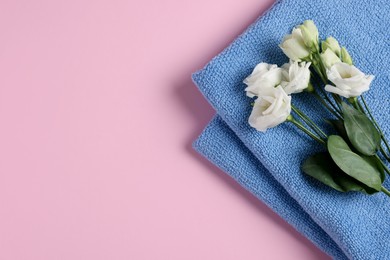 Photo of Soft folded blue towel with flowers on pink background, top view. Space for text
