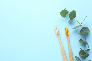 Toothbrushes made of bamboo on light blue background, flat lay. Space for text