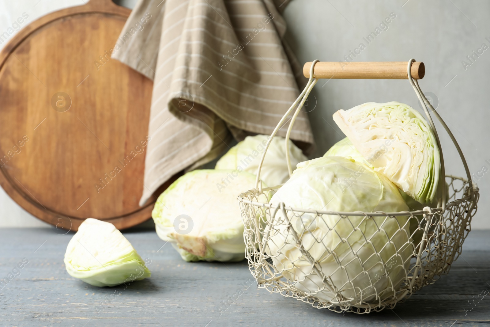 Photo of Basket with fresh cabbages on grey wooden table