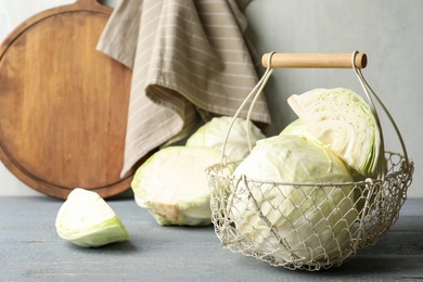 Photo of Basket with fresh cabbages on grey wooden table