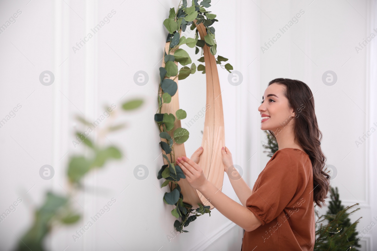 Photo of Woman decorating mirror with eucalyptus branches at home