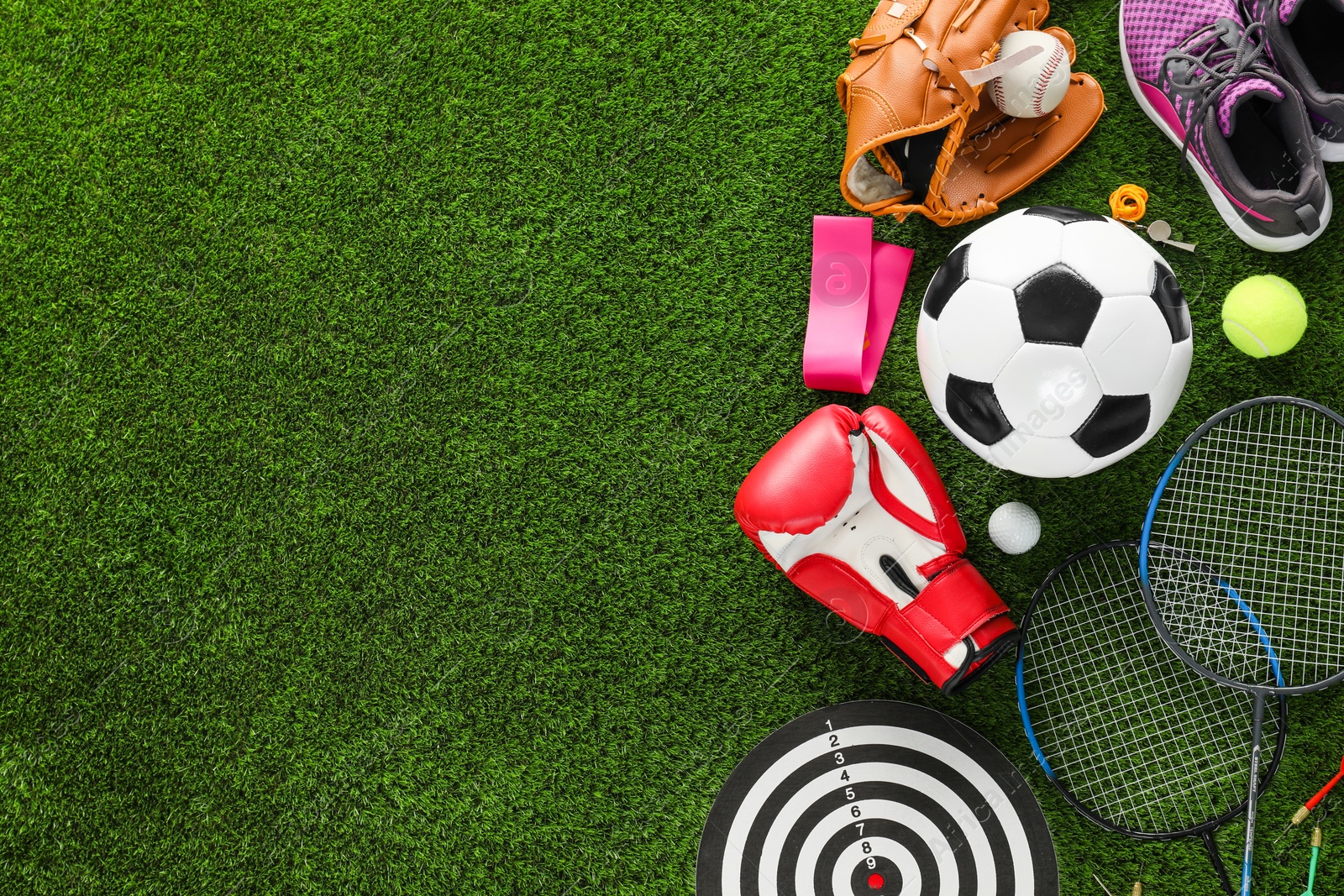 Photo of Different sport equipment on green grass, flat lay. Space for text