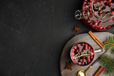 Photo of Tasty hot cranberry tea with rosemary, anise and cinnamon on black table, flat lay. Space for text