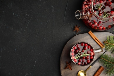 Tasty hot cranberry tea with rosemary, anise and cinnamon on black table, flat lay. Space for text