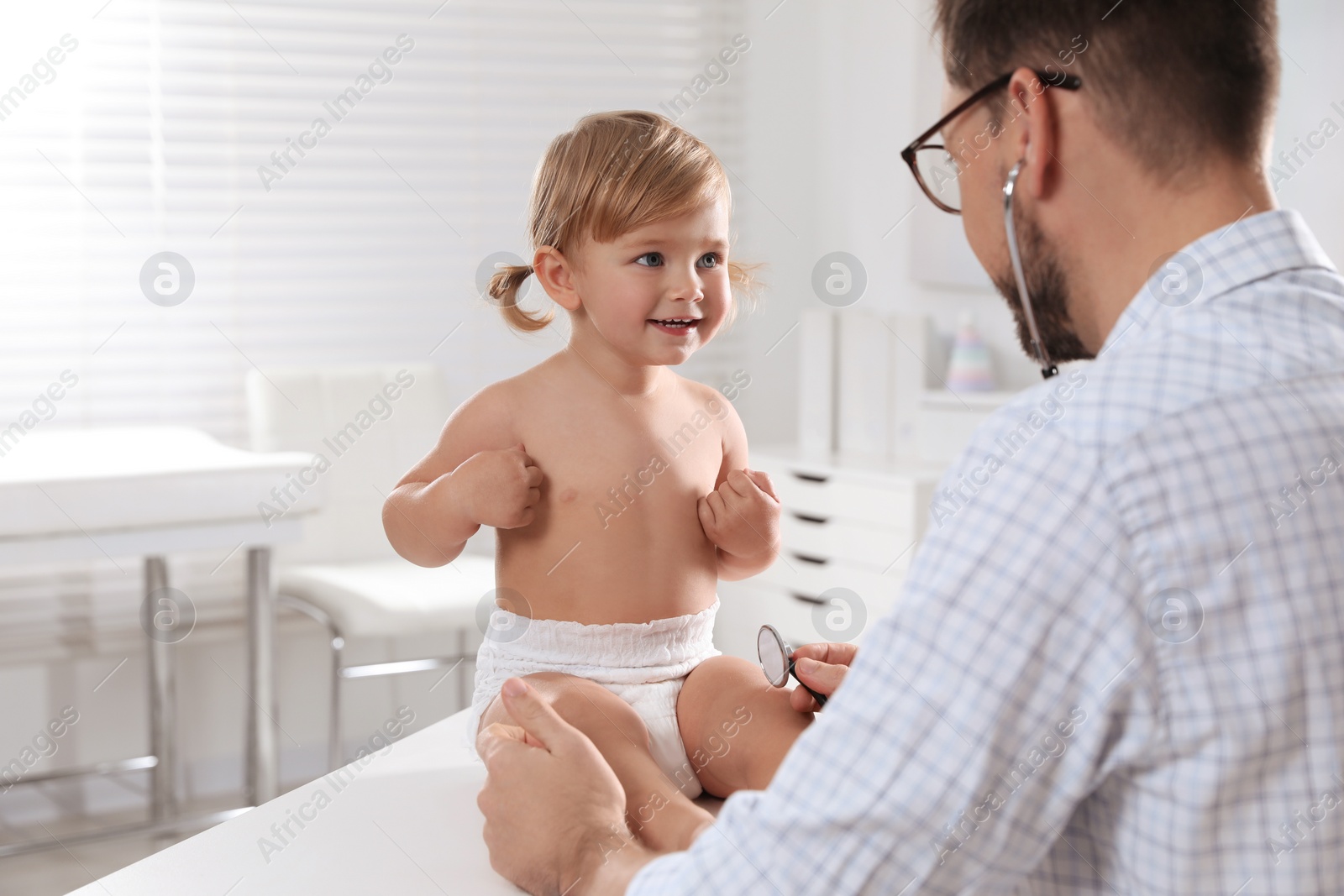 Photo of Pediatrician examining baby with stethoscope in clinic