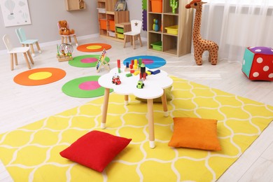 Child`s playroom with different toys and furniture. Cozy kindergarten interior