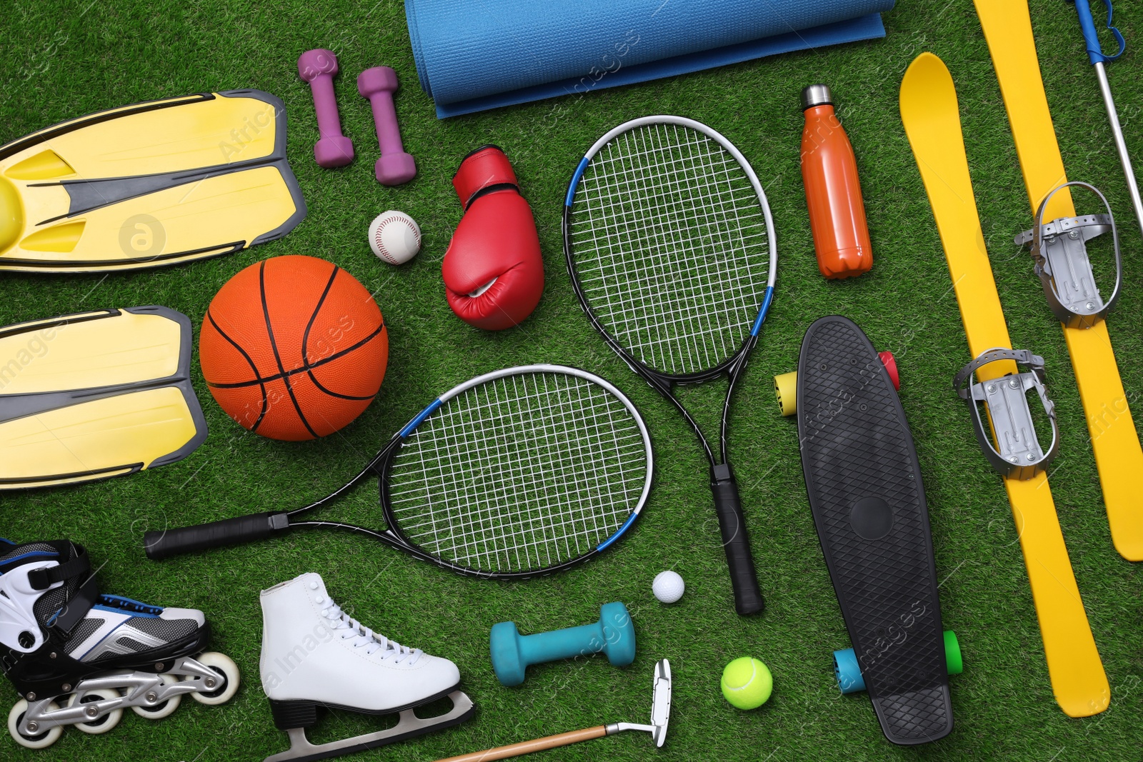 Photo of Different sport equipment on green grass, flat lay