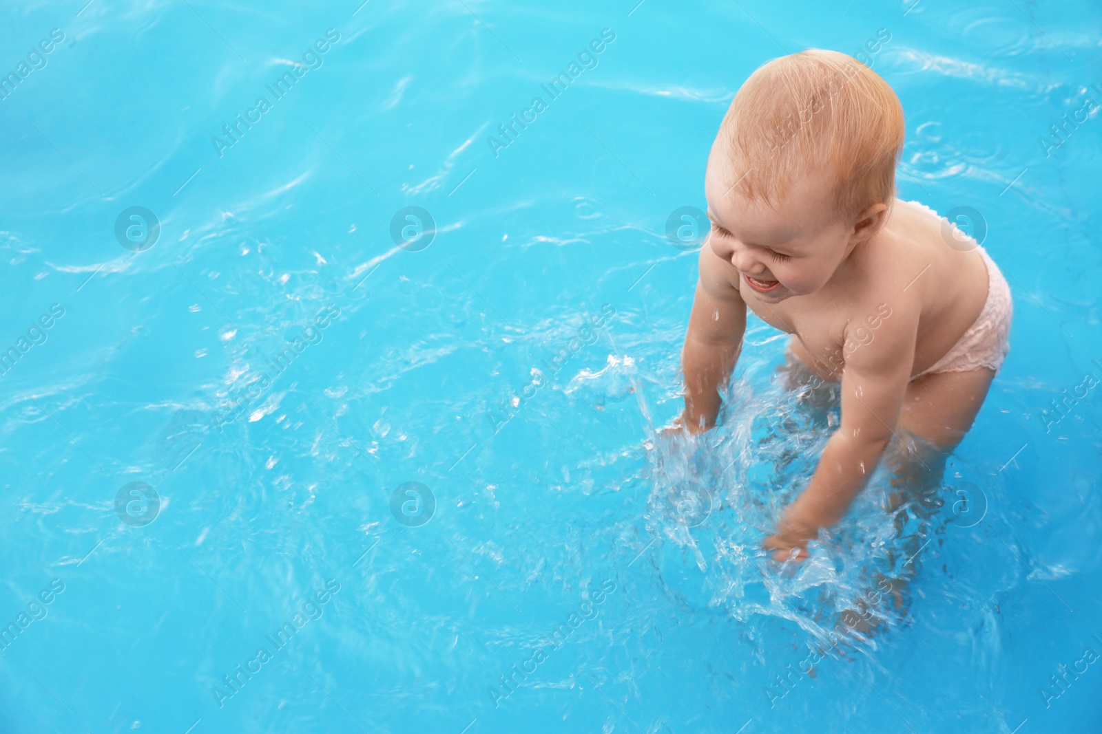 Photo of Little baby playing in outdoor swimming pool. Dangerous situation