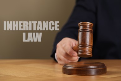 Image of Phrase Inheritance law and judge with gavel at wooden table, closeup