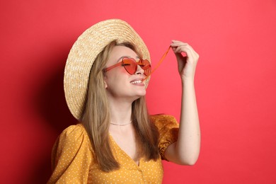 Fashionable young woman chewing bubblegum on red background