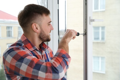 Photo of Construction worker adjusting installed window with screwdriver indoors