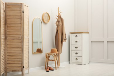 Photo of Hallway interior with wooden furniture near light wall. Stylish accessories