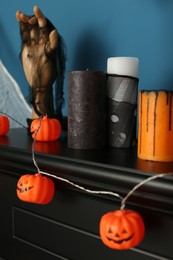 Photo of Jack-o'-lanterns and candles on black fireplace near blue wall
