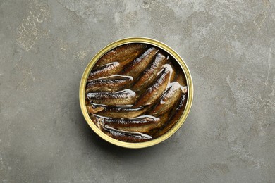 Photo of Sprats in tin can on grey textured table, top view