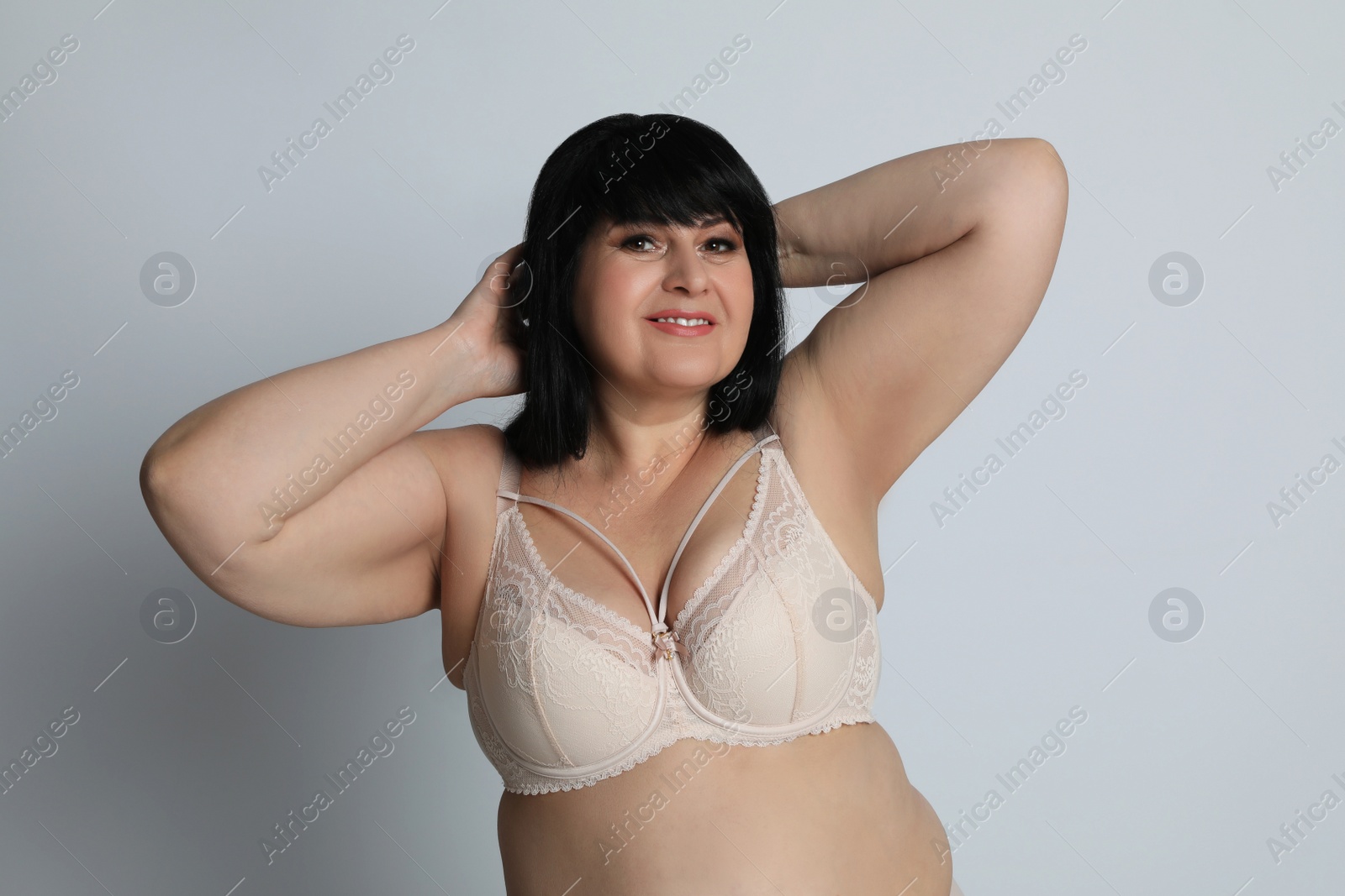 Photo of Beautiful overweight woman in beige underwear on light background. Plus-size model