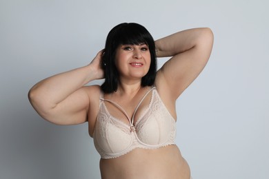 Photo of Beautiful overweight woman in beige underwear on light background. Plus-size model