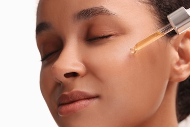 Photo of Beautiful woman applying serum onto her face on white background, closeup
