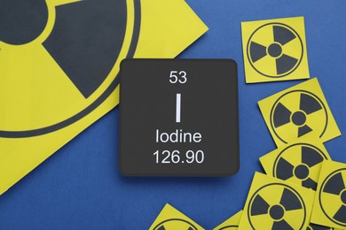 Photo of Card with chemical element Iodine and radiation signs on blue background, flat lay
