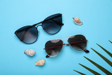 Photo of Stylish sunglasses and seashells on light blue background, flat lay