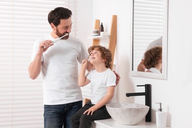 Photo of Father and his son brushing teeth together in bathroom