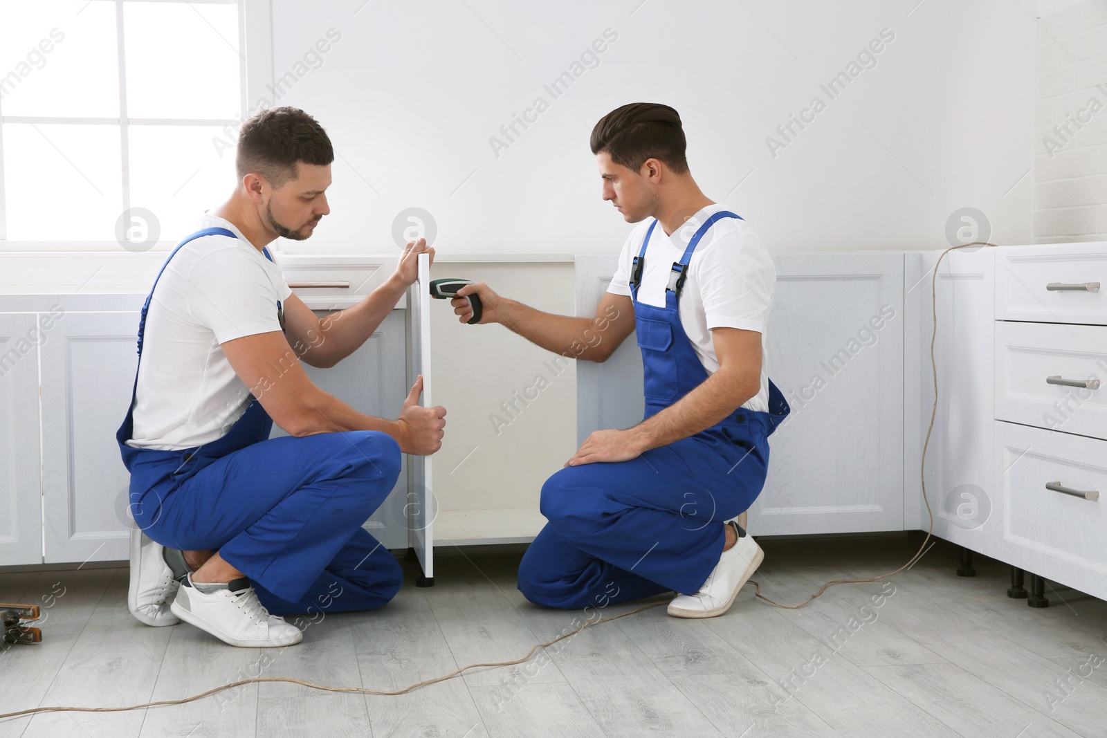Photo of Maintenance workers installing new kitchen furniture indoors