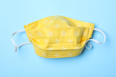 Photo of Homemade protective mask on light blue background, top view. Sewing idea
