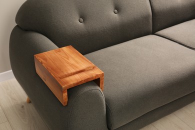 Photo of Wooden armrest table on sofa in room. Interior element