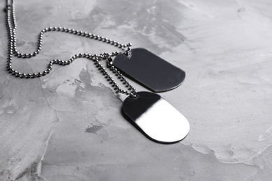 Photo of Blank military ID tags on grey stone surface, space for text
