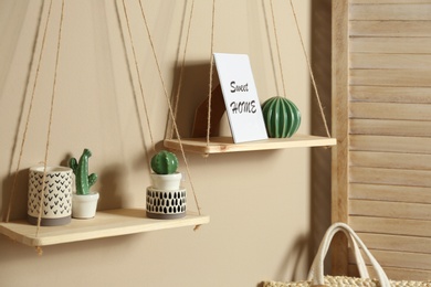 Photo of Wooden shelves with different decorative elements on beige wall