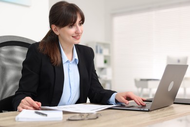 Photo of Smiling secretary working at table in office
