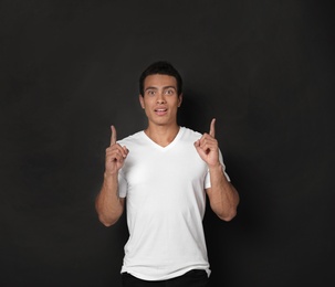 Photo of Handsome young African-American man pointing up on black background