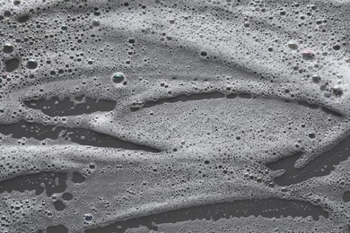 Photo of White washing foam on dark gray background, top view