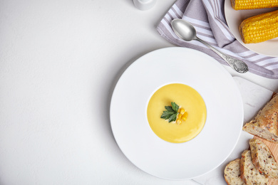 Photo of Delicious corn cream soup served on white table, flat lay. Space for text