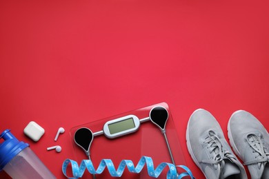 Photo of Flat lay composition with electronic scales and measuring tape on red background, space for text