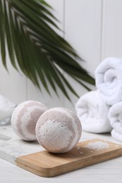 Photo of Bath bombs, sea salt and rolled towels on white wooden table, space for text