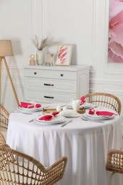 Photo of Color accent table setting. Plates, cutlery and pink napkins in dining room