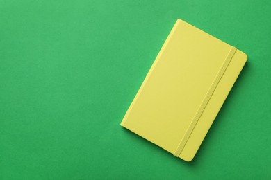 Photo of New stylish planner with hard cover on green background, top view. Space for text