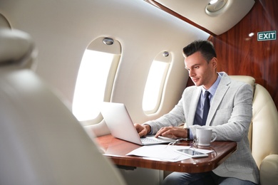 Image of Young man working with laptop on plane. Comfortable flight