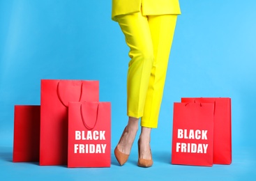 Photo of Woman with shopping bags on light blue background, closeup. Black Friday