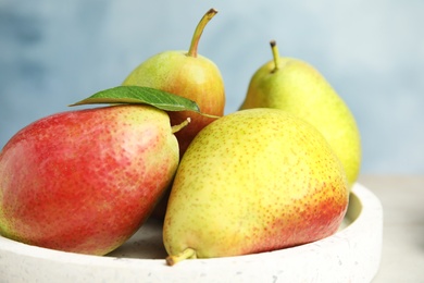 Photo of Plate with ripe juicy pears against blue background, closeup