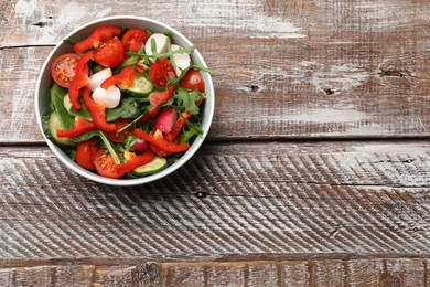 Photo of Tasty fresh vegetarian salad on wooden table, top view. Space for text