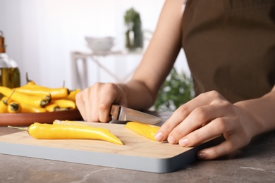 Photo of Woman cutting chili peppers at table, closeup