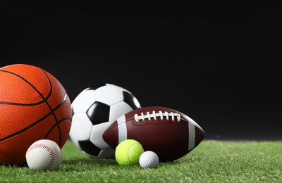 Many different sports balls on green grass against black background, space for text