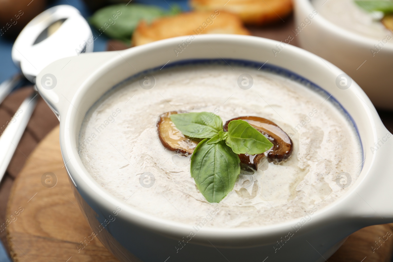 Photo of Fresh homemade mushroom soup served on blue wooden table, closeup