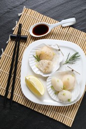 Photo of Raw scallops with green onion, rosemary, lemon and soy sauce on dark textured table, top view