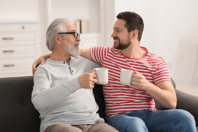 Photo of Happy son and his dad with cups at home