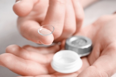 Photo of Woman holding contact lens and case, closeup